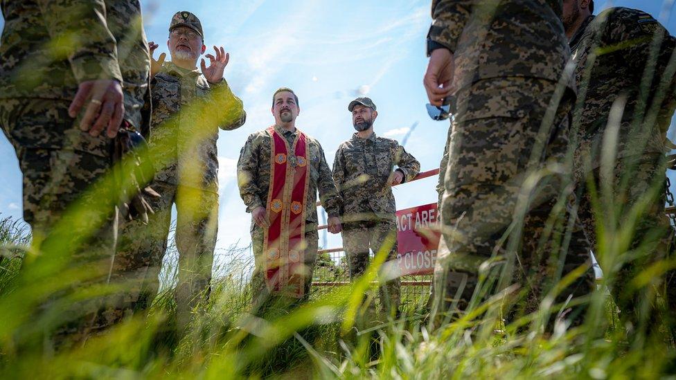 Ukrainian military chaplains talk with each other on the range area as several chaplains complete their training alongside Ukrainian soldiers and British Army training staff at a camp close to Warminster, Wiltshire.