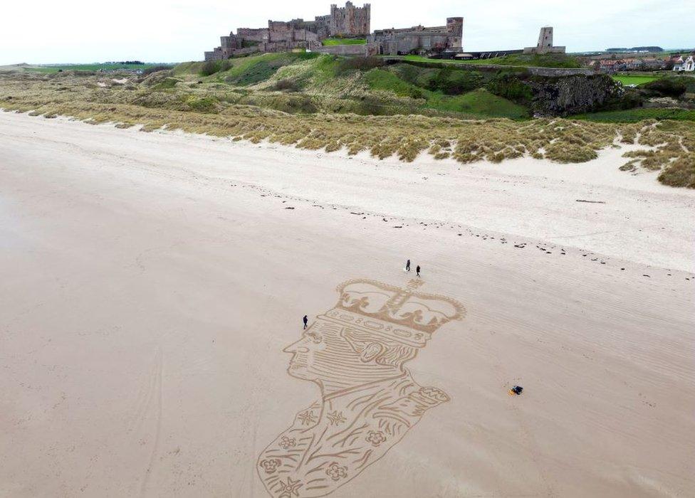 Aerial view of a sand sculpture of King Charles III wearing a crown sculpted into beach sand