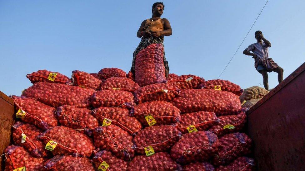 Labourers look on as they unload bags filled with onions at a wholesale vegetable market in Chennai on February 1, 2020.