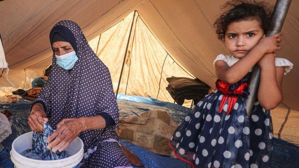 A Palestinian woman and a young child in a tent