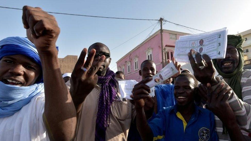 Voters gesturing and holding up ballot papers in Mauritania