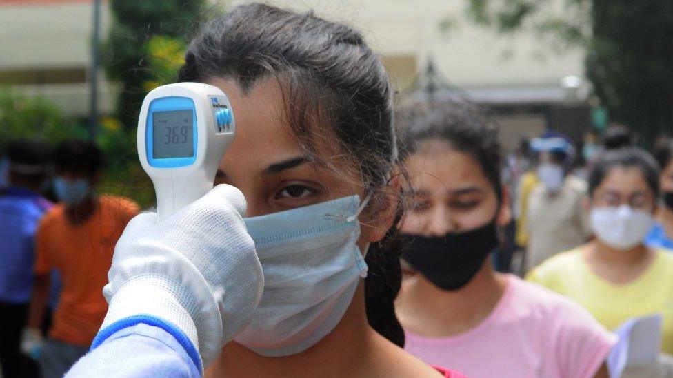 A temperature check is carried out on a student waiting to enter the exam centre at Khalsa School, on September 13, 2020 in Chandigarh, India