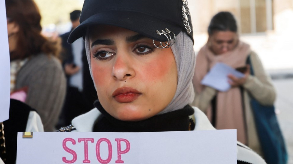 A woman holding a sign saying 'stop'