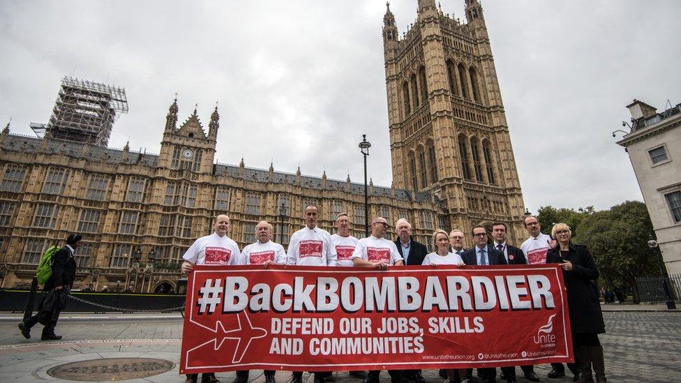 Workers from the Bombardier factory in Belfast hold a banner to highlight their situation