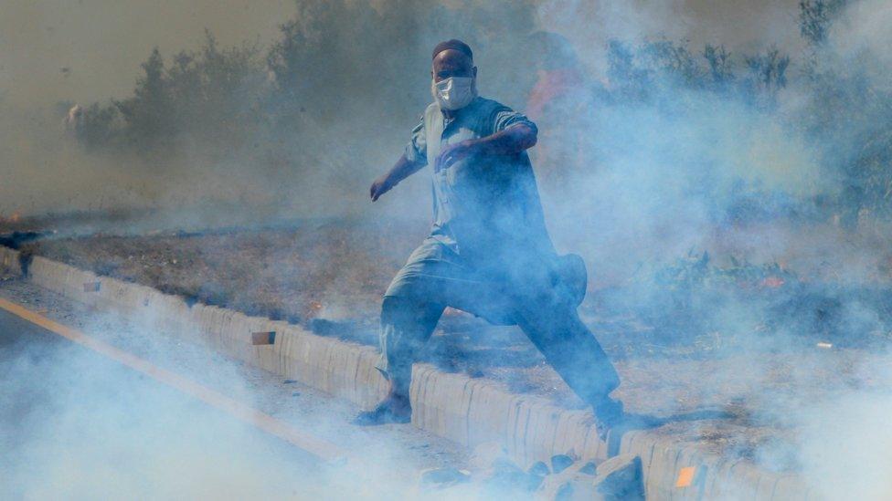 A supporter of Pakistan's former prime minister Imran Khan, runs amid tear gas fired by police during a protest rally in Swabi on May 25, 2022.