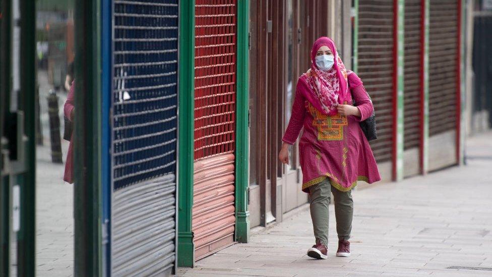 Woman in facemask walks past closed Cardiff shops