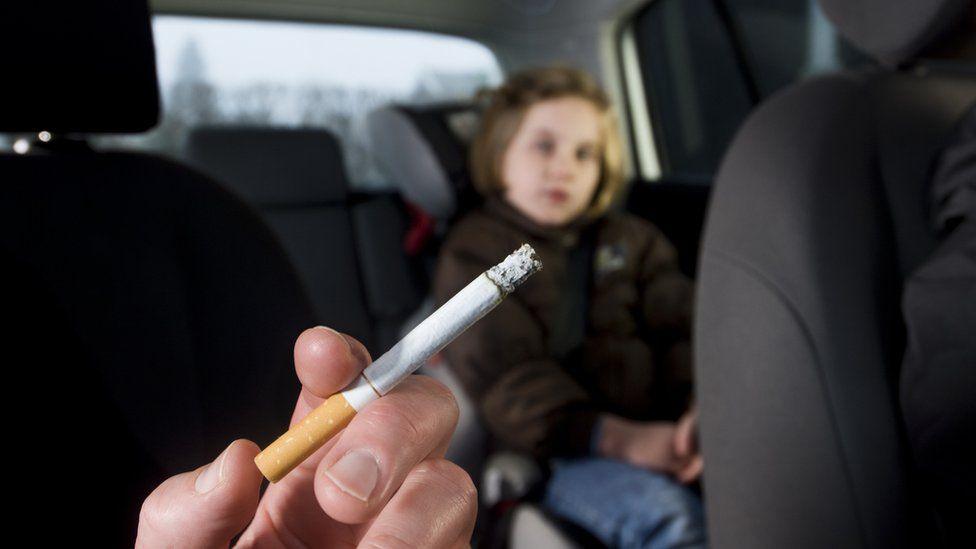 Someone smoking in a car with a child in the back seat