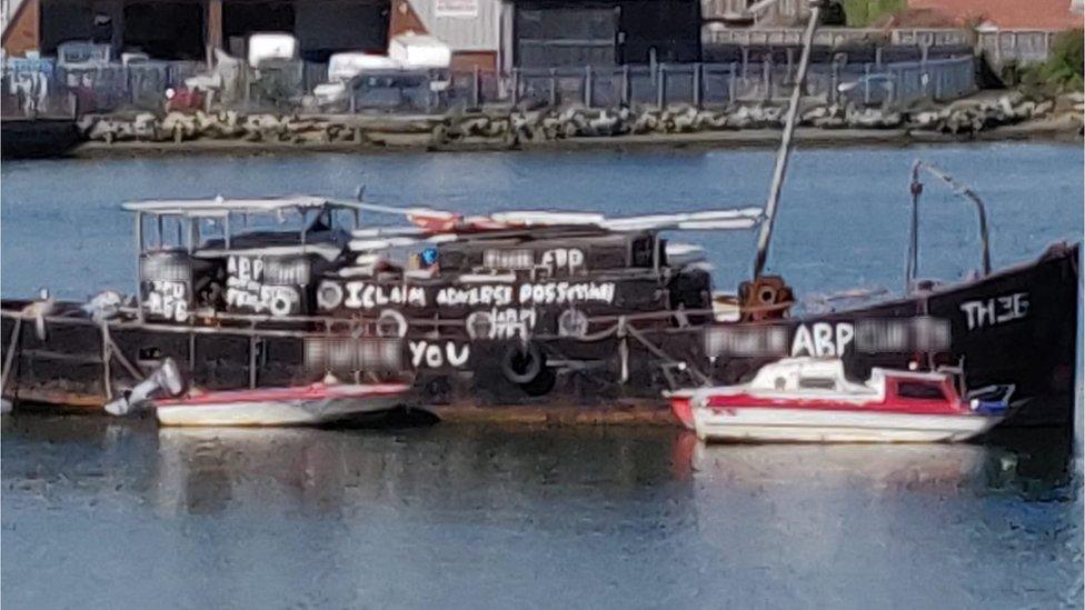 A black boat daubed with swear words painted in white graffiti