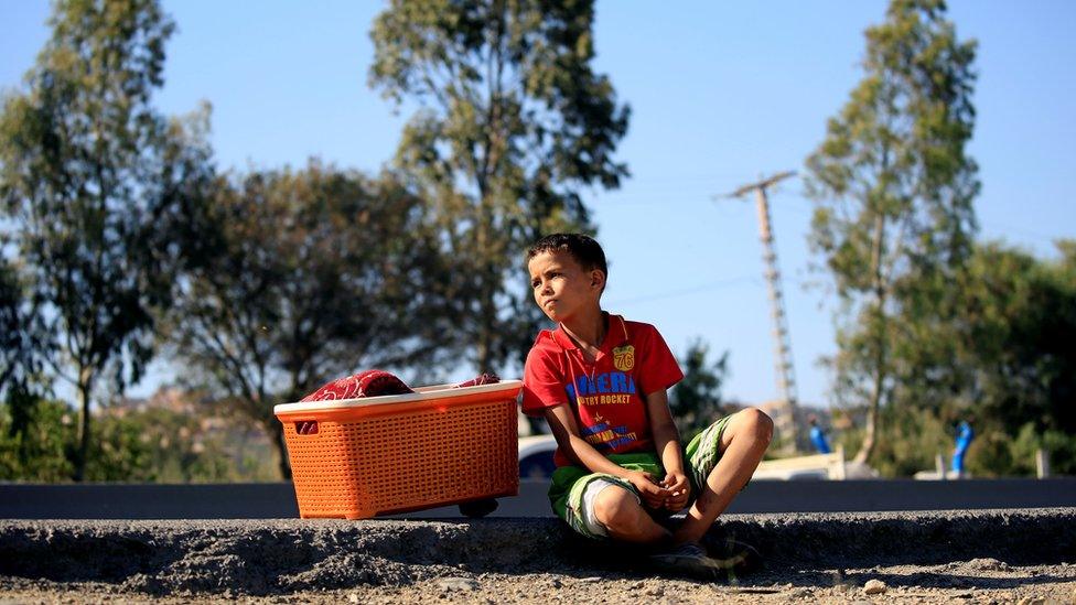 A boy and waits with a box of traditional breads by the roadside on the outskirts of Algiers, Algeria - 13 June 2016