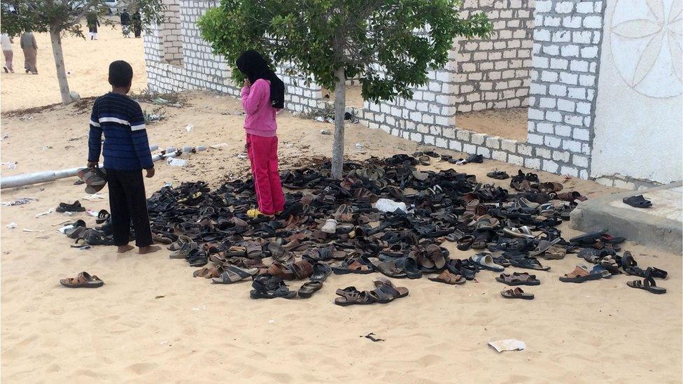 Egyptian children stand near a pile of footwear belonging to the victims of the Rawda mosque attack, Egypt, 25 November 2017