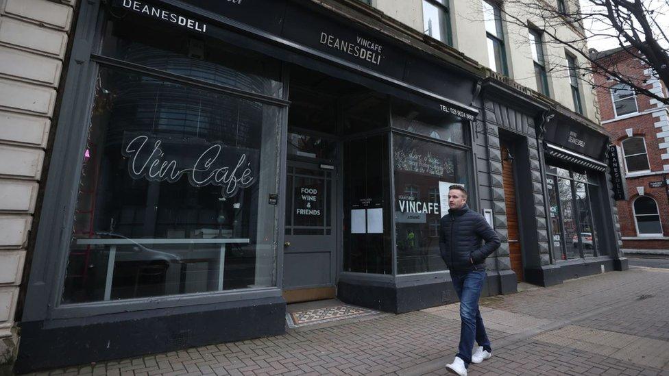 Man walks past a closed restaurant in Belfast in February 2021