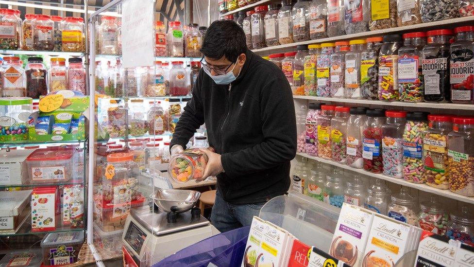 A man weighs out sweets in a sweet shop