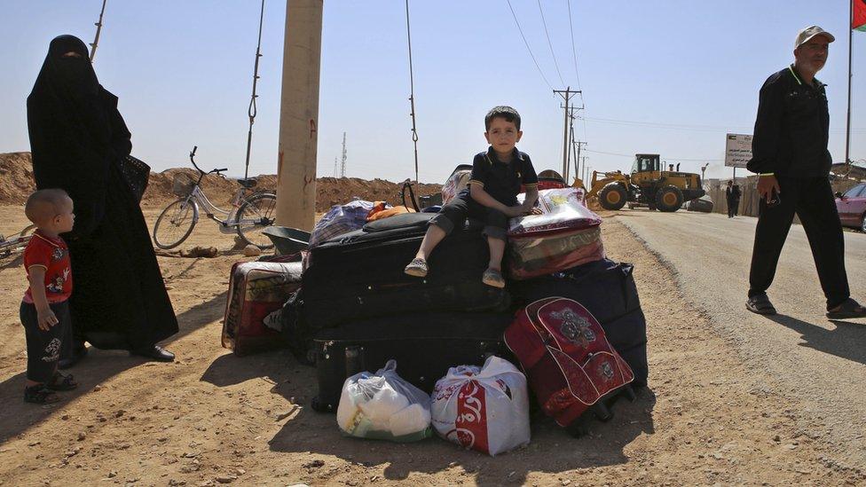 Boy sitting on suitcases waiting to leave the Syrian refugee camp in Zaatari, Jordan