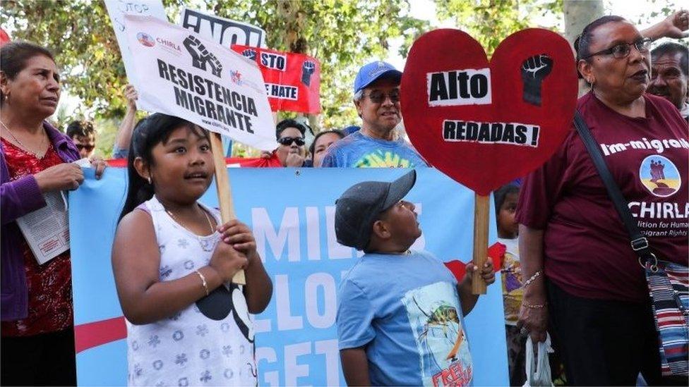 Protesters at a rally in Los Angeles, hold signs (14 June 2018)