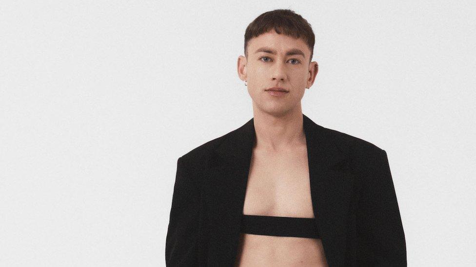 Olly Alexander looking at the camera wearing a black jacket