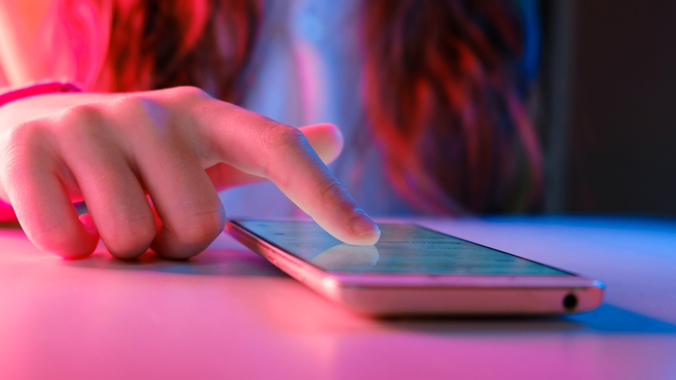 A stock image of a woman scrolling a phone screen