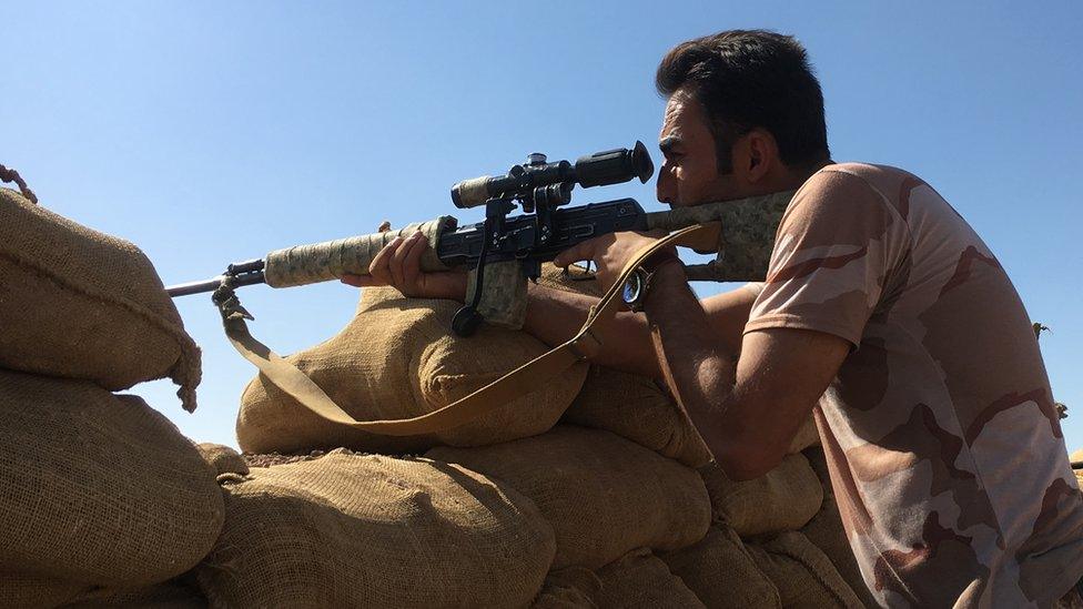 A Kurdish Peshmerga fighter aims down the sight of a sniper rifle over sandbags on Bashiq Mountain, 12km from Mosul