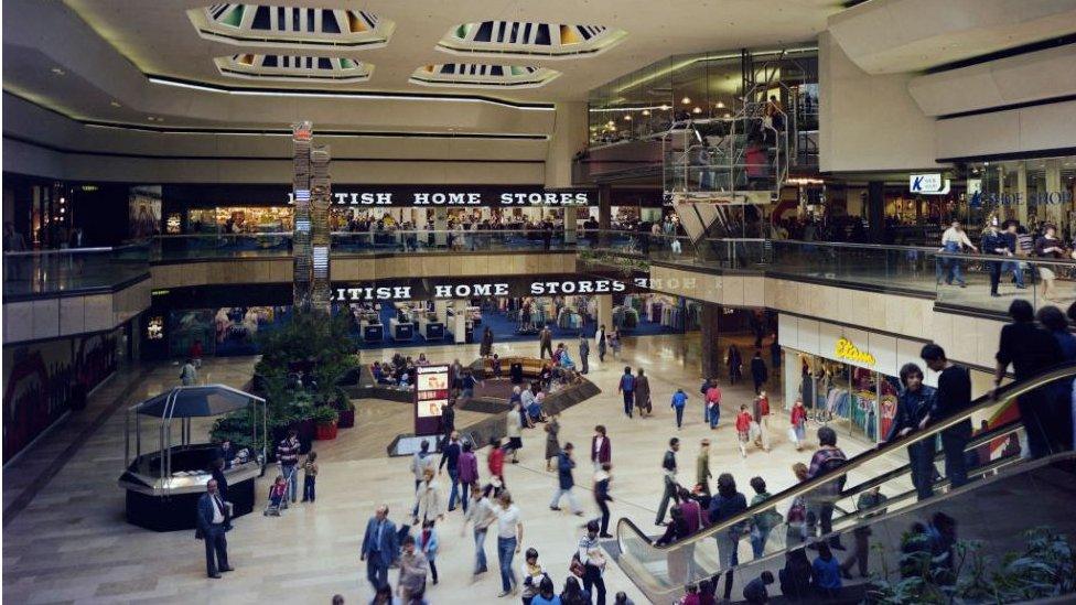 An interior view of Queensgate Shopping Centre taken from the Central Square escalator, showing the entrance to British Home Stores in 1982