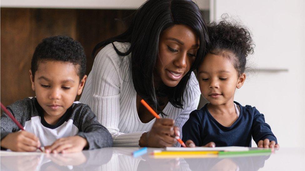 Kids being helped with schoolwork by mother