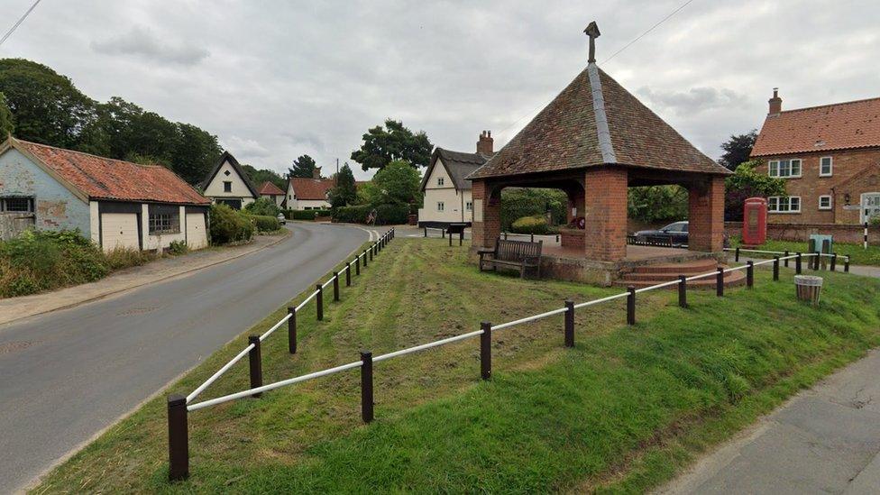 View of Saxlingham Nethergate with war memorial, thatched cottages and red phone box