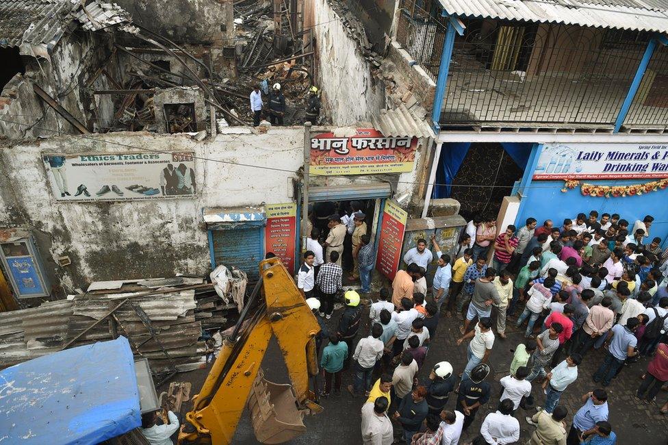 Indian policemen inspect a sweet shop destroyed by a fire on 18 December in Mumbai.