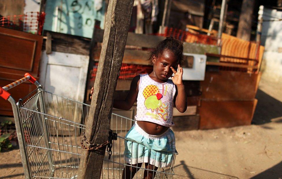 A young girl stands in a shopping cart in the poverty ridden City of God favela, or slum, on December 2, 2009 in Rio de Janeiro