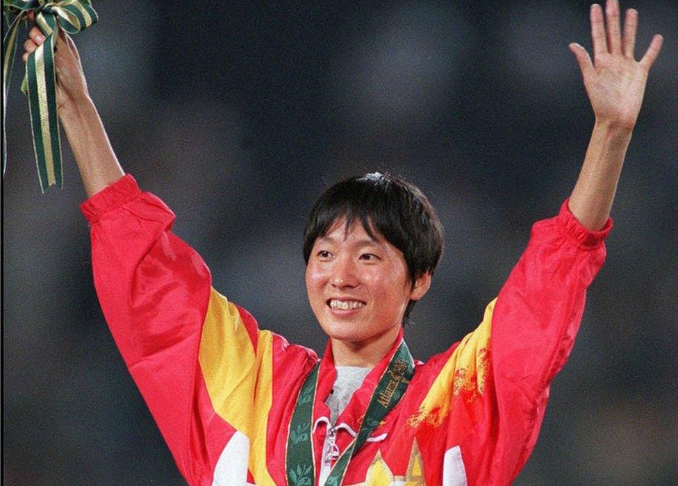 Wang Junxia from China celebrates on the podium during the medal ceremony after winning the gold medal in the women's Olympic 5,000m event at the Olympic Stadium in Atlanta, Georgia, 28 July 1996