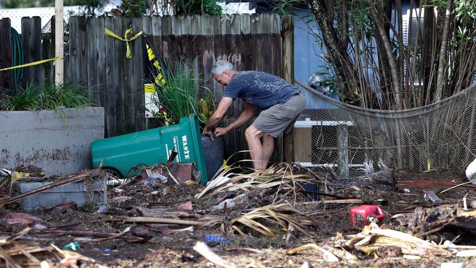 A business owner clears debris outside his office after Hurricane Hermine passed through Friday, 2 September 2016, in Cedar Key, Florida