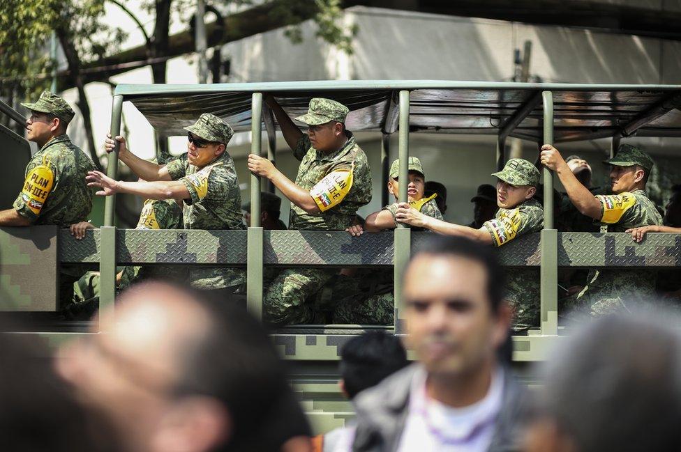 Mexican troops pictured in a vehicle wear a telltale yellow armband that shows they are responding to a disaster