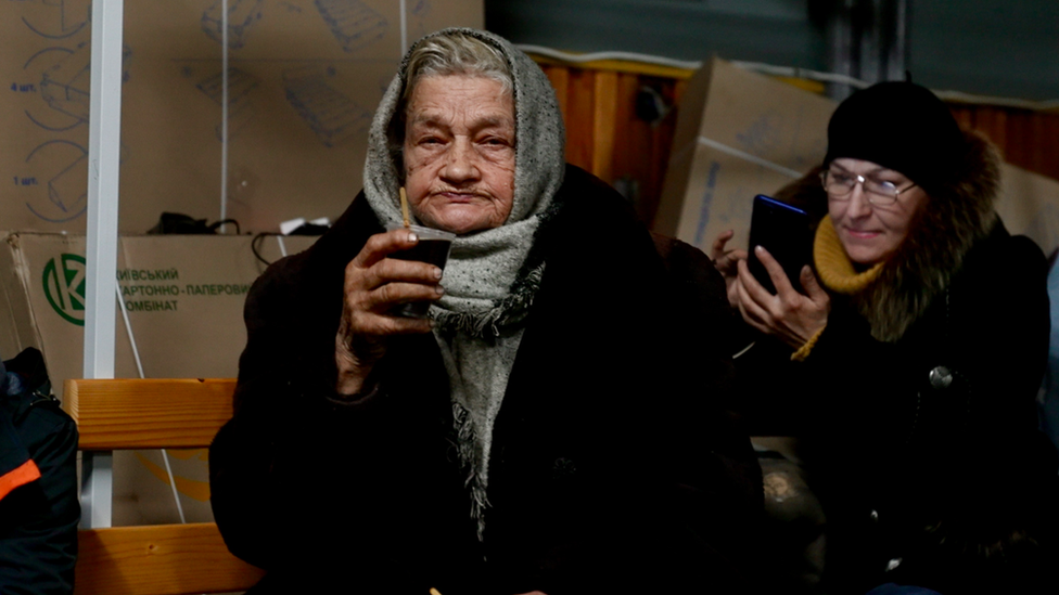 Women charge their phones and drink tea in Bakhmut