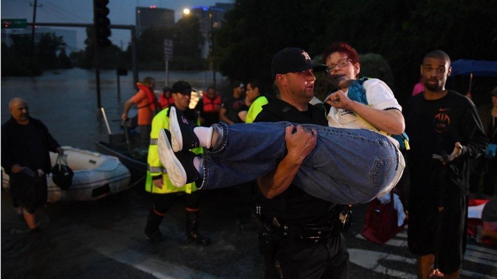 A woman is carried after being rescued from a hotel by boat due to heavy flooding by Hurricane Harvey in Houston