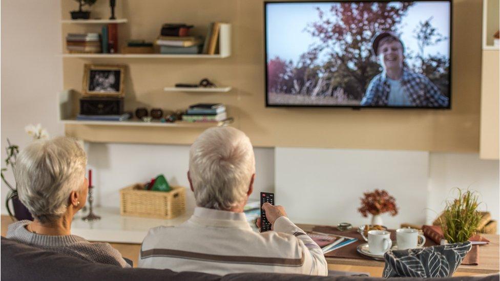 Couple sitting watching television stock image