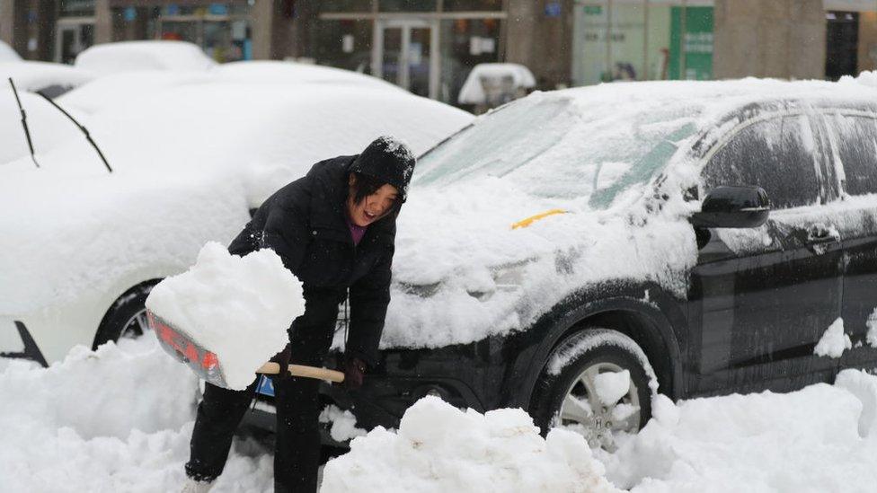 A woman clears snow from her car after a snowfall on November 9, 2021 in Shenyang, Liaoning Province of China.