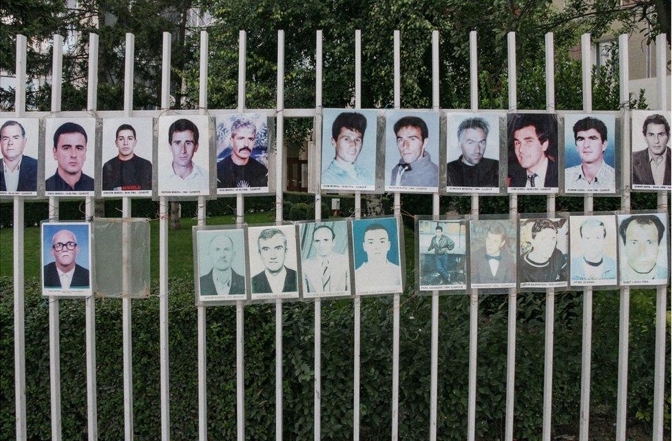 A fence with photos of missing men attached to the railings