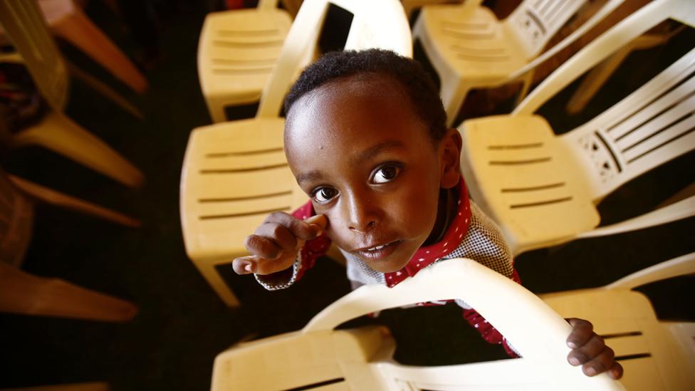 A child stands between chairs in a large tent where migrants are gathered following a press conference during which Sudanese security forces presented them to journalists at the defence ministry in the capital Khartoum on 30 August 2016