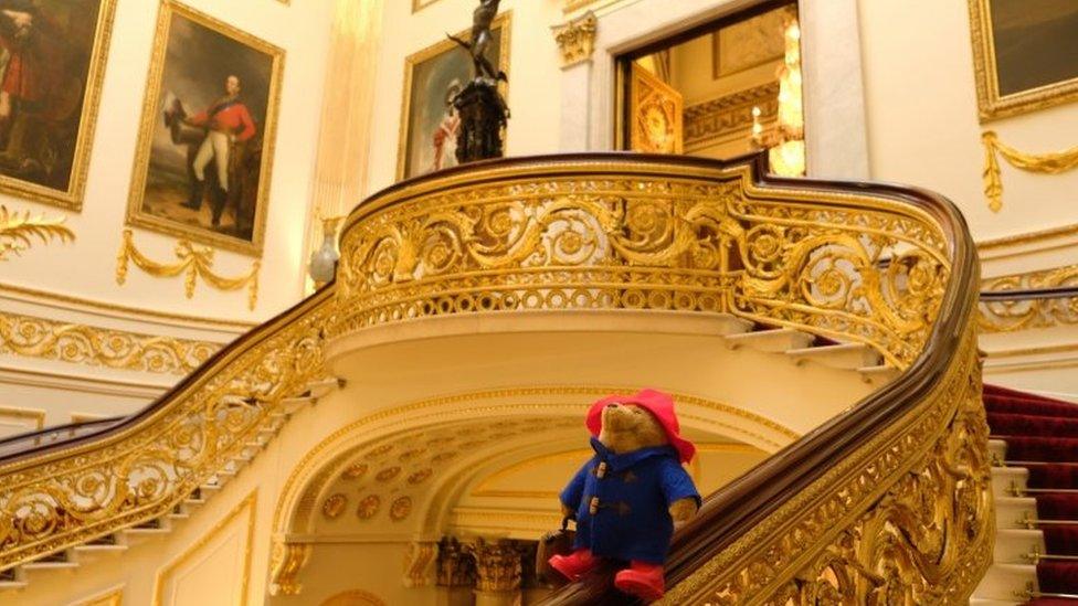 Paddington Bear sat on the Grand Staircase at Buckingham Palace in London