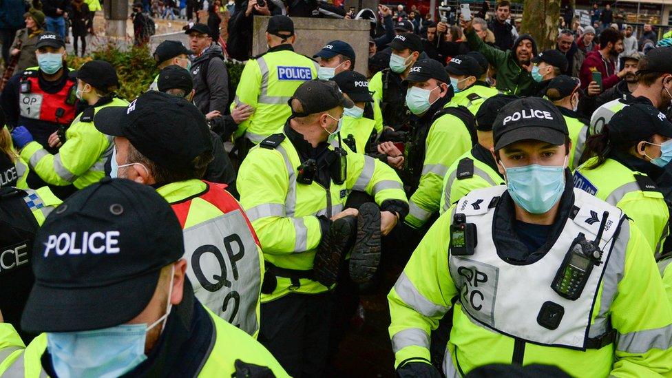 Police officers arrest an anti-lockdown protester in Bristol