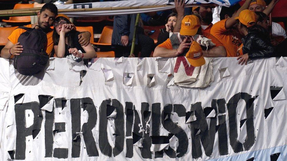 Supporters standing over a sign that reads "Peronismo" appear sad