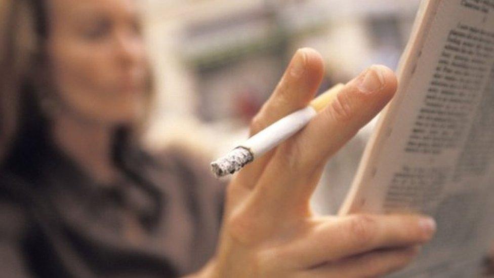 A woman holding a cigarette and reading a newspapers