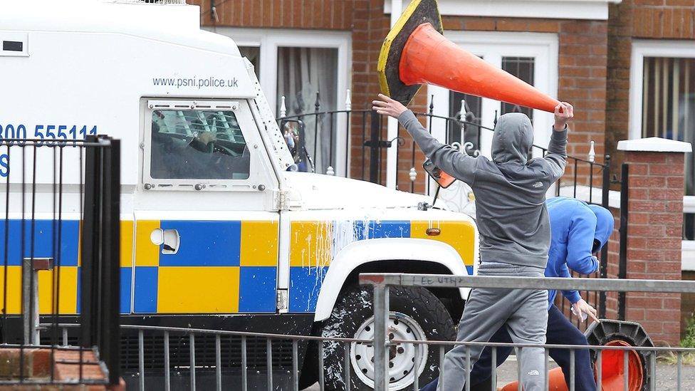 Youth lifts traffic cone next to police vehicle