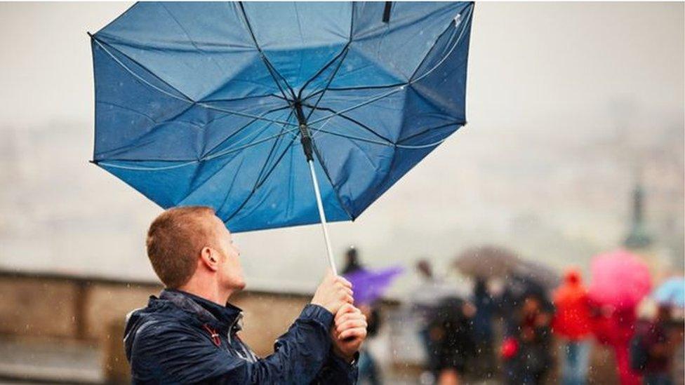 A man holding an umbrella caught by wind