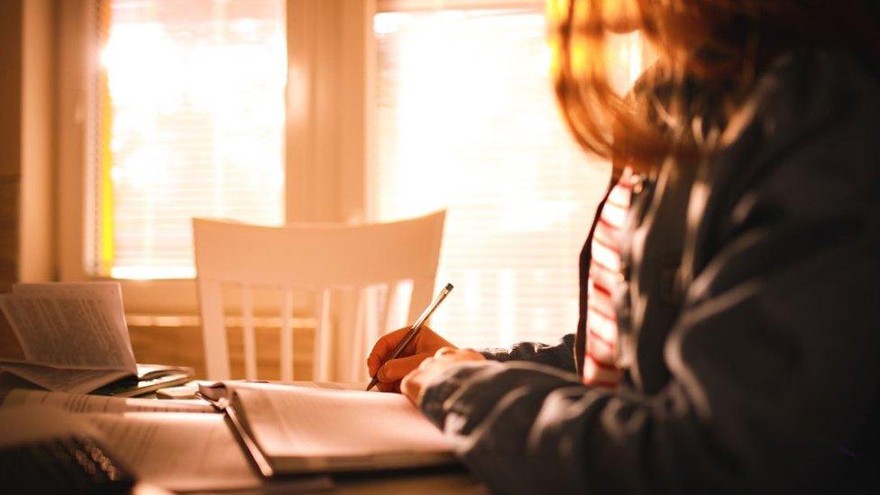 A girl sits at a table doing homework