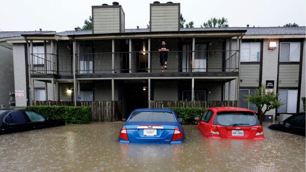 A resident looks out from the second floor as floodwaters surround his apartment complex Monday, April 18, 2016, in Houston