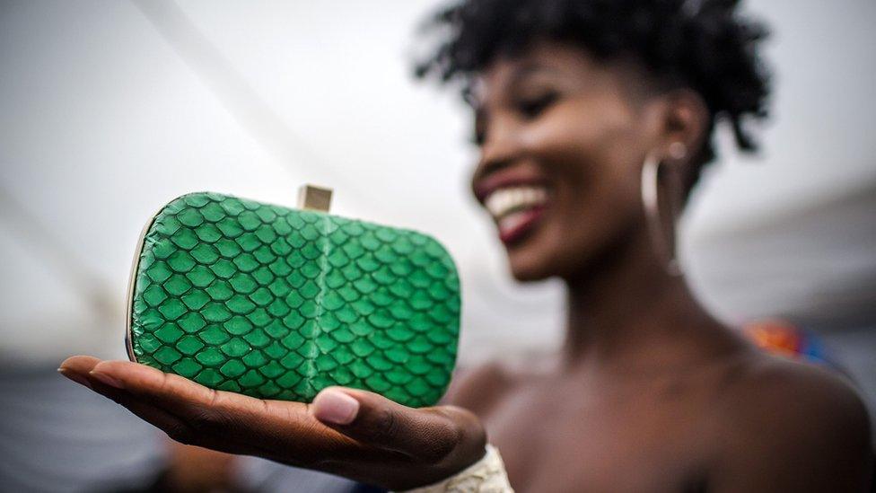 Model holds a green fish skin clutch