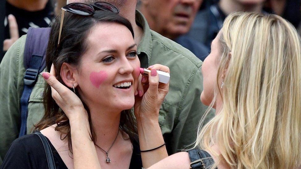 Two women decorate their faces with pink hearts close to the starting line