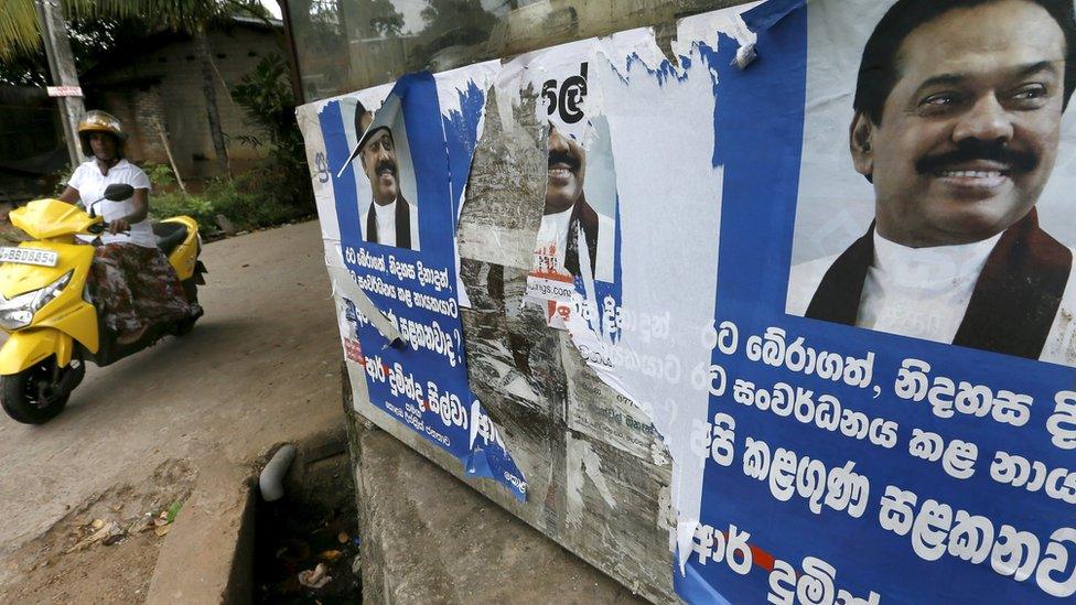 A woman rides her bike past election posters of Sri Lanka's former Sri Lankan president Mahinda Rajapaksa for the upcoming general election