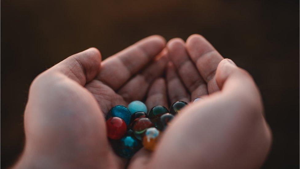 Hands holding marbles.