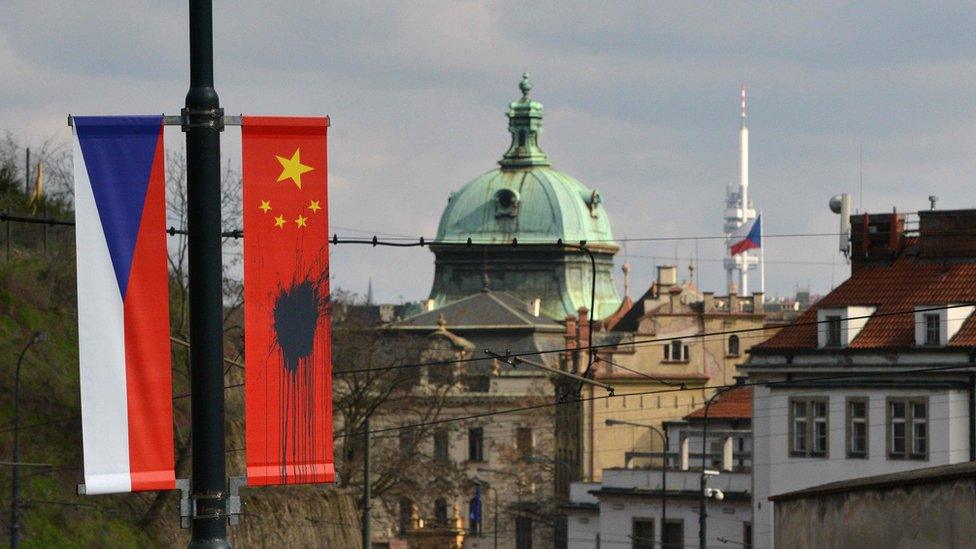 A Czech National flag hangs next to a Chinese National flag splattered with a black substance in Prague on March 26, 2016