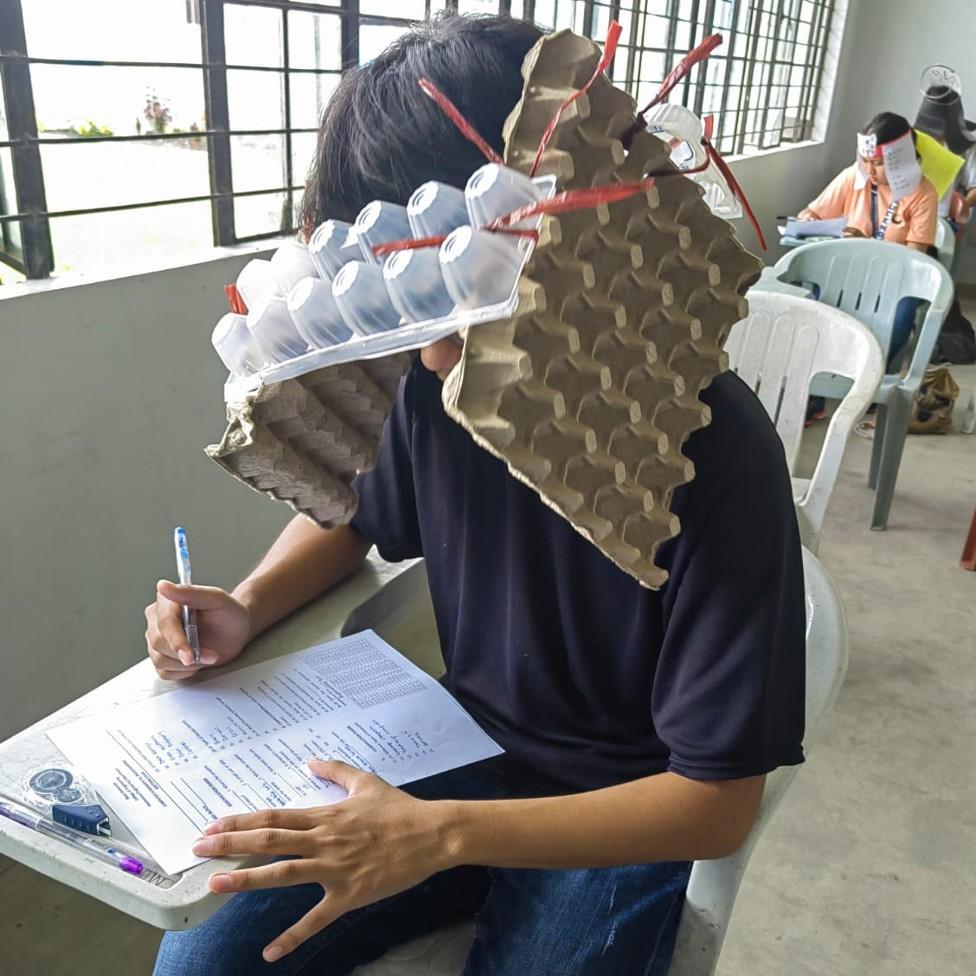 A student wears a homemade hat made of egg boxes during a college exam in the Philippines