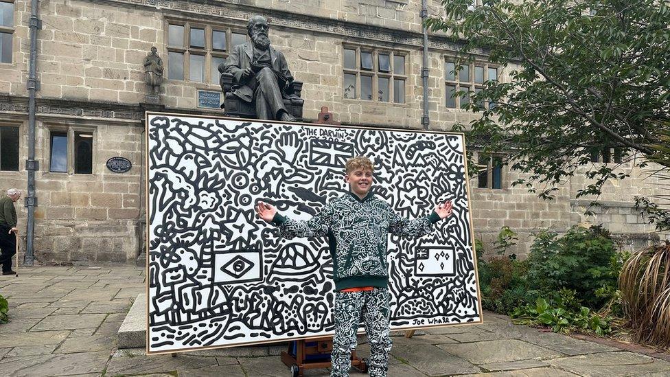 Doodle boy with a piece of art outside Darwin's school